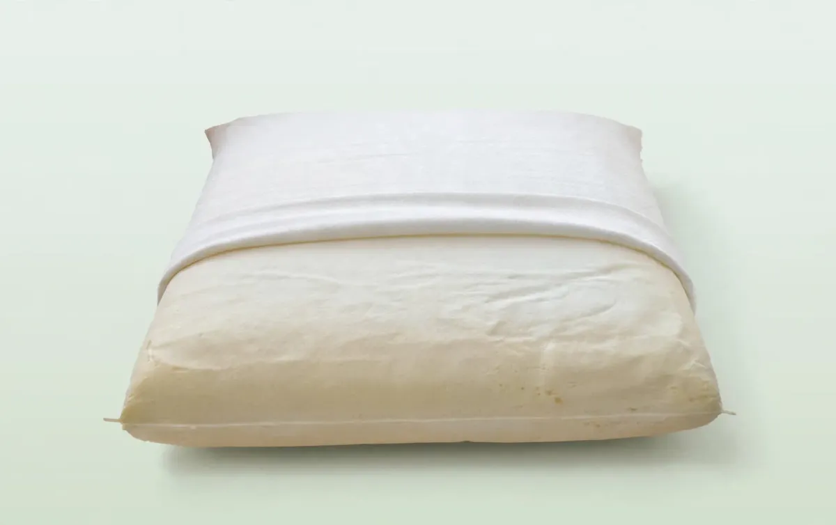 Guanciale in memory foam con la fodera abbassata a metà: si vede l'anima color crema